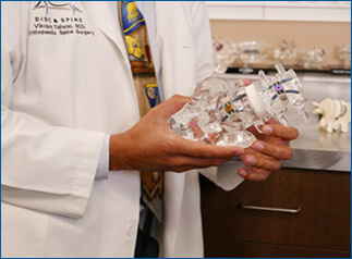 Close up of doctor showing a detailed see through plastic model of a spine
