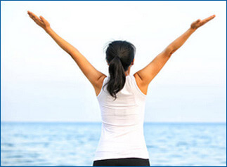 Wide shot of woman with streched out arms looking off into the horizon